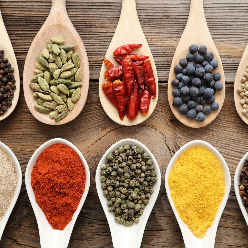 Assortment of natural spices on vintage spoons on dark slate